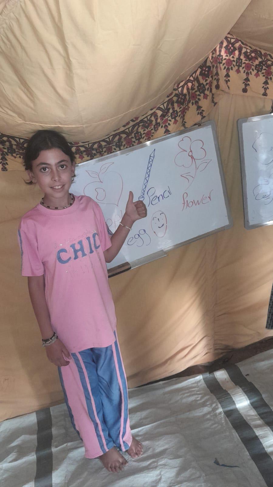 Girl pointing at a whiteboard mounted inside the new tent