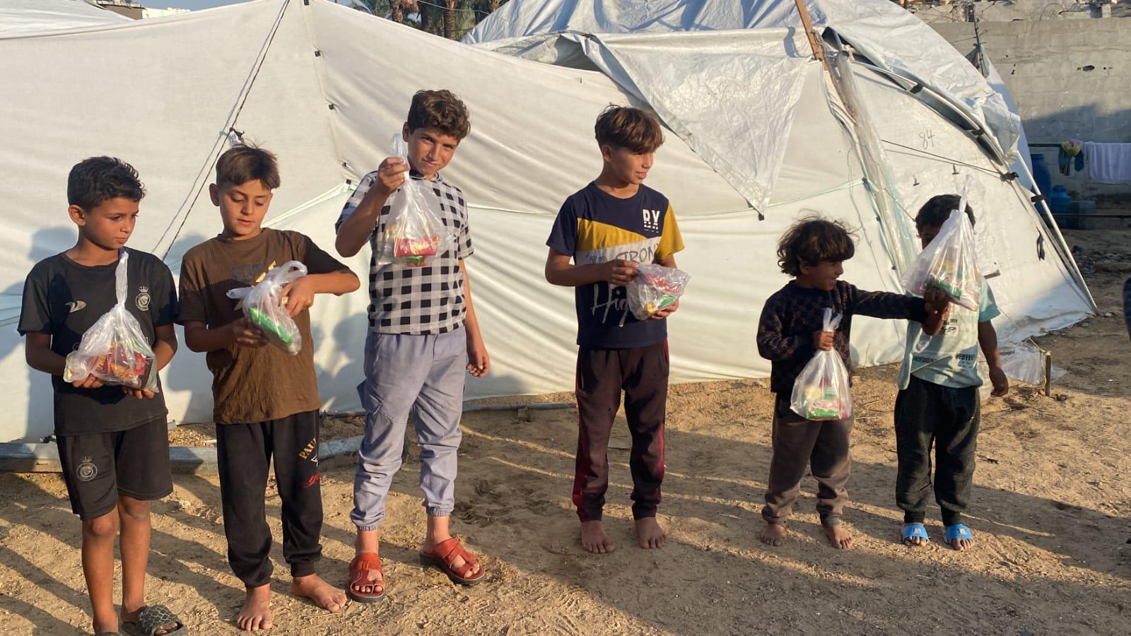 Children holding their new snack packs outside the new tent