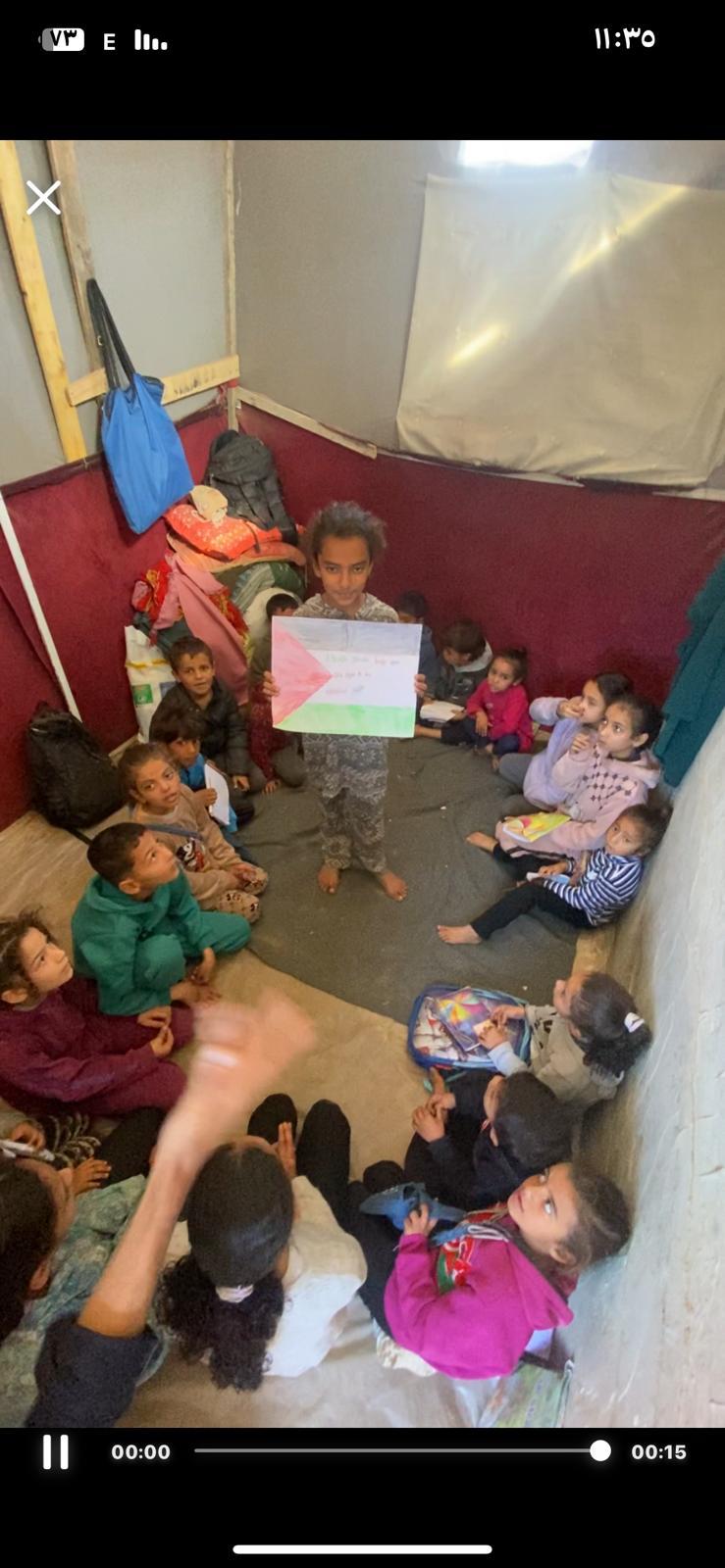 Boy holding a hand-drawn Palestinian flag inside the school tent