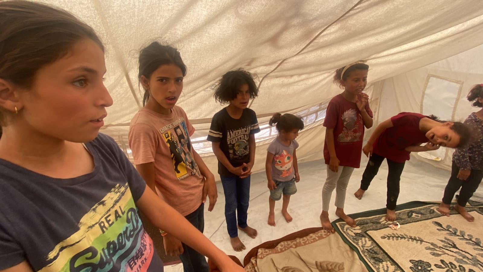 Children sitting together inside the school tent